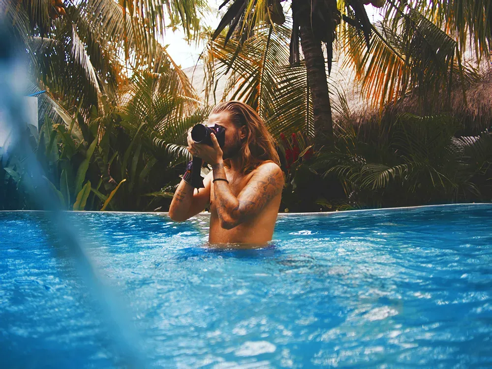 Man in Pool with camera taking photo speak easy magazine