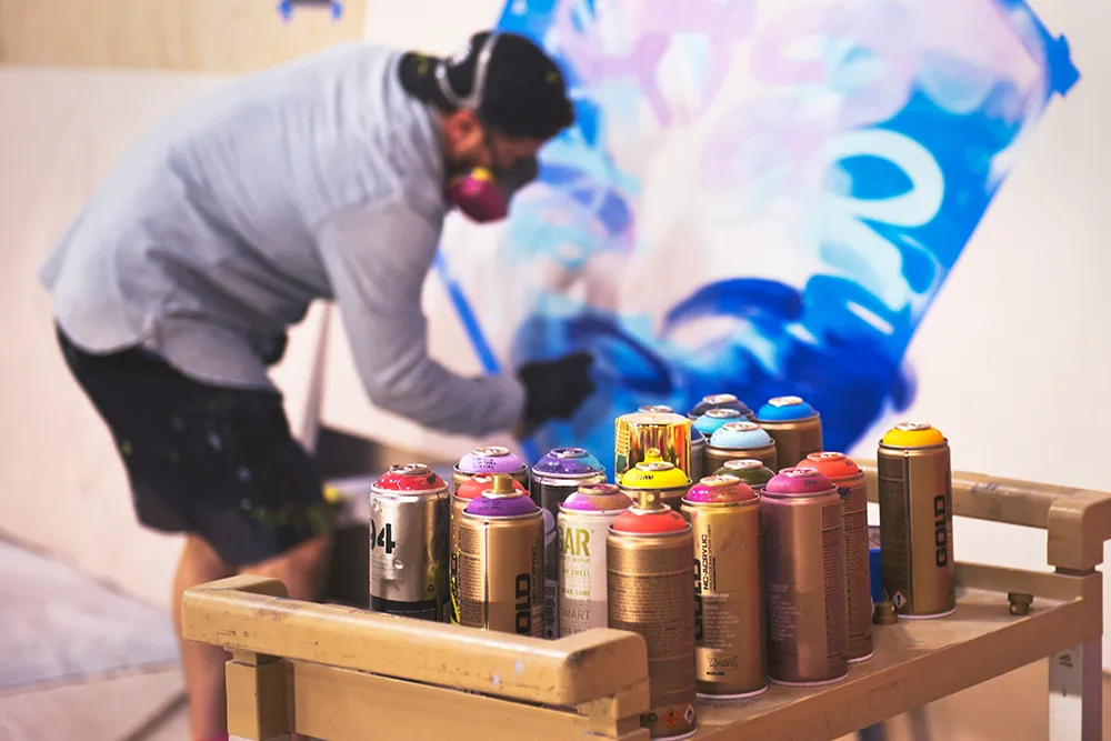 Man with face mask spray paints street art