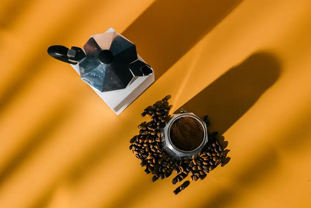 Coffee beans and maker on yellow background