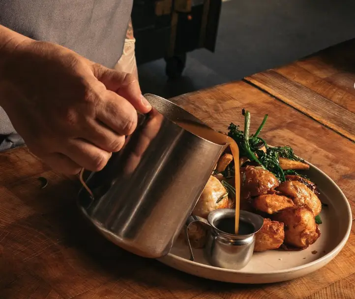 person pouring gravy on roast